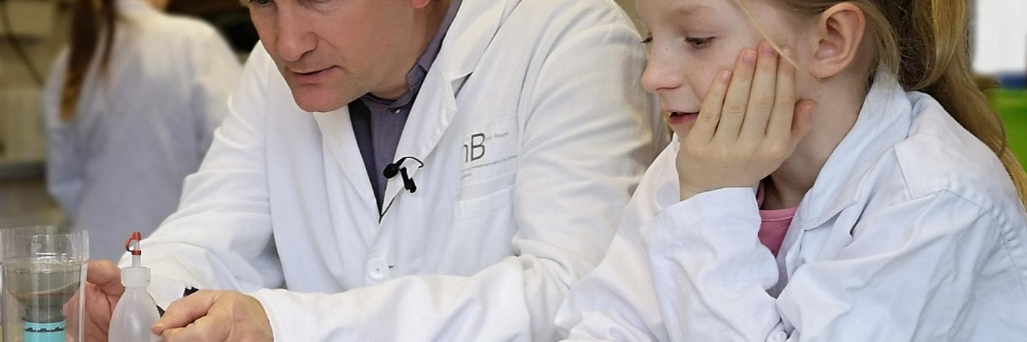 Wissenschaftler und Kind beobachen ein Experiment