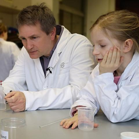 Wissenschaftler und Kind beobachen ein Experiment