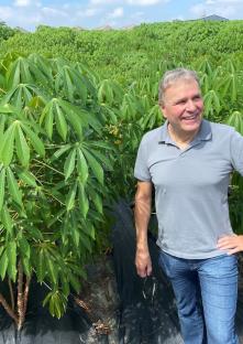 Ekkehard Neuhaus an einem Versuchfeld, umrahmt von Maniok-Pflanzen.